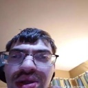 Man wearing glasses looking into the camera with a confused and slightly distorted facial expression.