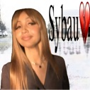 Woman with long brown hair posing next to the text Sybau and a red broken heart icon.