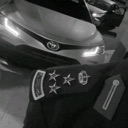 Police shoulder epaulet with stars and insignia displayed in front of a blurred patrol car.