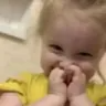 Child giggling with hands covering their mouth in a playful expression.
