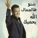A man in a dark suit waving with a wide, charming smile and Arabic text next to him.