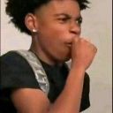 Young man covering his mouth with his hand while looking off to the side with a suspicious expression.