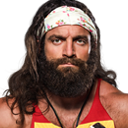 Elias with a long beard and headband looking directly at the camera with a serious expression.