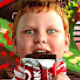 A young boy with ginger hair and wide, intense eyes eating a chocolate bar.