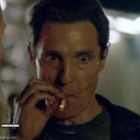 Matthew McConaughey as Rust Cohle staring intensely while holding a lit cigarette.