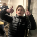 A young boy giving a double thumbs-up gesture towards the camera.