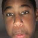 A person's face shown in a tight, slightly blurry close-up with a neutral and skeptical expression.