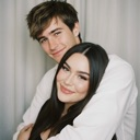A young man and woman smiling while embracing each other in a soft-focus portrait.