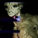 Grey alien with large black eyes and a serious expression.