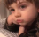A young child resting their chin on their hand with a bored and unimpressed expression.