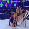 Asuka applying a submission hold to an opponent in a wrestling ring while a referee watches closely.