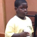 Young boy looking sideways with a suspicious and uncomfortable expression while holding a cup.