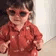 A toddler wearing red sunglasses looking cool and confident.