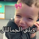 A toddler smiling with a pink digital bow filter on their head and Arabic text overlay.