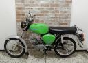 A bright green vintage Simson moped parked against a brick wall background.