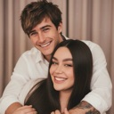A man and a woman smiling and hugging each other affectionately.