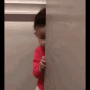 Baby peeking around a corner with a happy and mischievous smile.