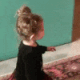 A toddler hugging another child while holding a red balloon.