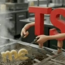 Red letters TS with human arms frying the word me in a metal pan.