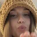 Person wearing a textured crochet bucket hat blowing a kiss towards the camera.