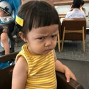 A young toddler with a yellow shirt looking sideways with a skeptical and judgmental expression.