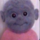A blue, doll-like creature with large, dark, unblinking eyes staring forward with a neutral expression.