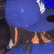 King Von wearing a blue LA hat and blue shirt in a dark, club-like setting.