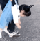 Toddler in blue overalls being dragged by an adult's legs while looking completely limp and exhausted.