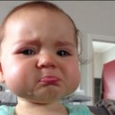 A baby with a tear-streaked face and a deeply pouting, sad expression.