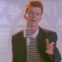 Rick Astley singing into a microphone in his classic 80s music video style.