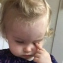 A toddler rubbing their eye with their finger while looking tired or annoyed.