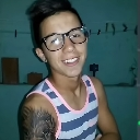 Young man with glasses and a tattoo smiling with a smug expression.