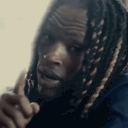King Von holding a finger to his lips in a shushing gesture.