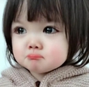 A toddler with a pouty expression and large eyes looking slightly off-camera.