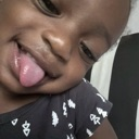 A toddler making a silly face while sticking their tongue out at the camera.