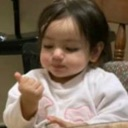 Toddler holding up one finger while looking down with a serious expression.