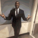 Shannon Sharpe standing in a suit with his arms outstretched in a gesture of disbelief.