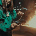 King Von performing a hand gesture with a fire background.