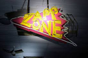 Zapp Zone neon sign glowing in yellow and red against a dark background.