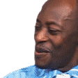 A man with a shaved head wearing a blue striped shirt looks to the side with an exaggerated, surprised expression while the …