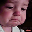 A toddler with a deeply exaggerated, teary-eyed pout looking sad.