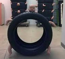 A baby's head and limbs are sticking out from the center of a black car tire.
