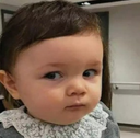 A toddler looking to the side with a skeptical and unimpressed facial expression.