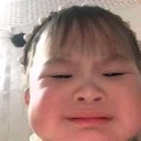 A child with a squinty, skeptical expression looking directly at the camera.