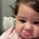 Baby with a sad, pouting expression and teary eyes looking directly at the camera.