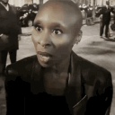 Cynthia Erivo looking shocked with a wide-eyed expression and holding up a hand in a gesture of disbelief.