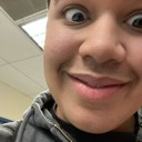 Person with a wide-eyed, intense, and mischievous grin looking directly into the camera.