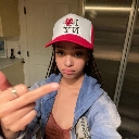 A young woman wearing an I Love NY hat holds up her middle finger to the camera.