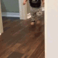 A toddler walking with a confident swagger across a wooden floor.