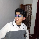 A teenager wearing blue-tinted sunglasses looking off to the side with a relaxed expression.